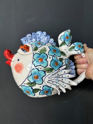 a hand holding a Blue Sky Clayworks Blue Flower Fish Teapot