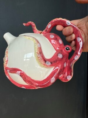 a hand holding a Blue Sky Clayworks Circular Red Octopus Teapot