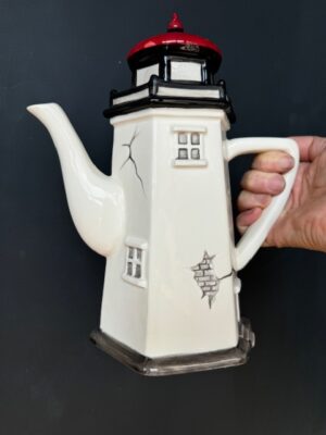 a hand holding a Blue Sky Clayworks Lighthouse Teapot