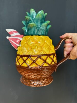 a hand holding a Blue Sky Clayworks Pineapple Teapot