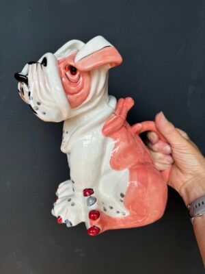 a hand holding a Blue Sky Clayworks Sweet Pea Pink Sitting Bull Dog Teapot