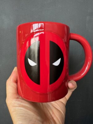 A hand holding Marvel Deadpool Suit mug face forward