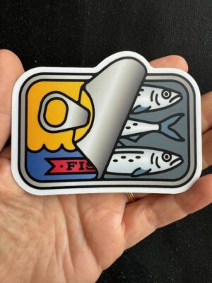 Hand holding a sticker with a sardine tin peeled back, showing three sardines