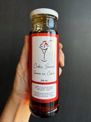 A bottle of Round Box Foods Cider Sauce being held by a hand