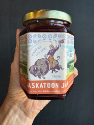 A jar of The Saskatoon Farm Jam being held by a hand