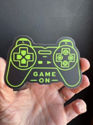 Vinyl sticker of a black game controller with green text 'game on'