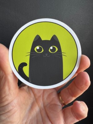 Vinyl sticker circle with green background and large black cat smiling with green eyes.