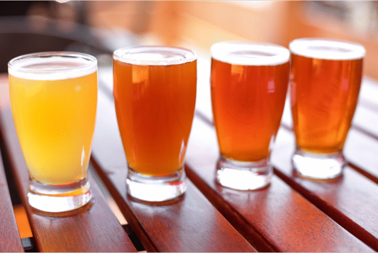 Four small glasses of beer set up for a beer flight