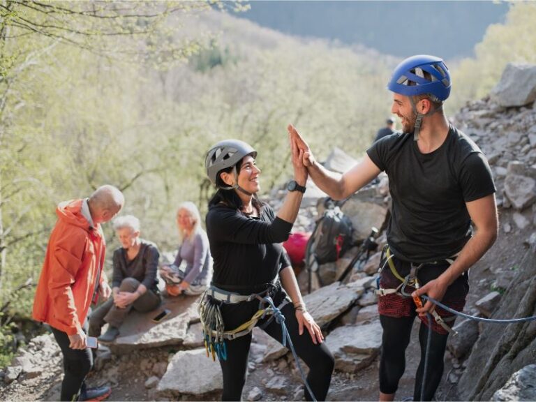 Rock Climbers high-fiving while wearing ropes and rock-climbing equipment
