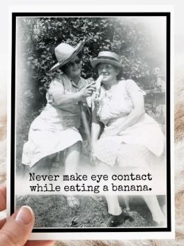 Raven's Rest Studio Greeting Card - "Never make eye contact while eating a banana" features vintage two ladies in black and white both holding a banana that one is eating.