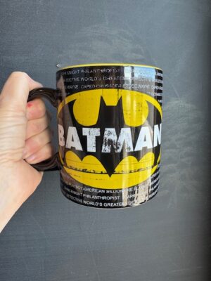 coffee mug with Batman logo in yellow overtop white text on black background