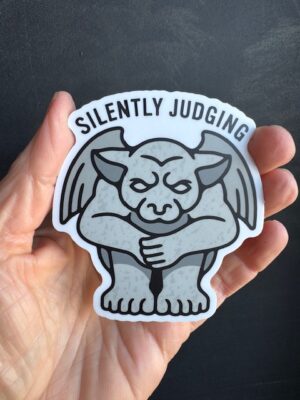 Vinyl sticker with grey hunched gargoyle and black text "Silently Judging"