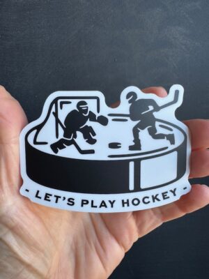 black and white vinyl sticker of a hockey puck with a goalie and player about to take a slapshot on it. Text under puck reads "Let's play hockey."