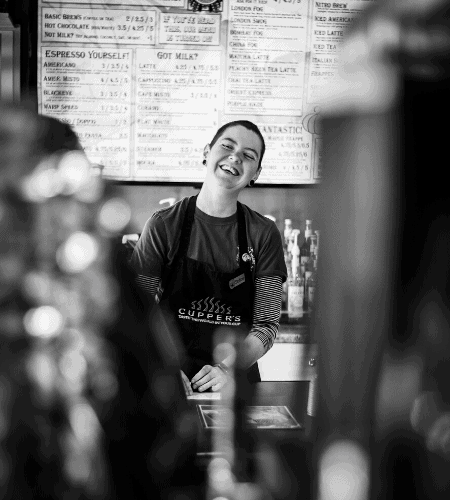 Stef in front of the drink menu of freshly roasted coffee