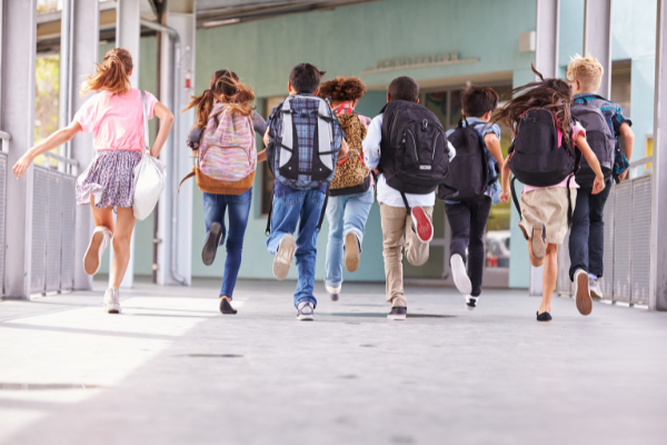 Fundraising for schools A group of children with backpacks on running down an outside corridor