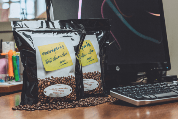 grinding coffee Workperks office coffee on a desk by a computer.