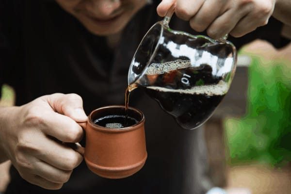 office brewing methods a man pouring a single serve coffee into a small brown mug